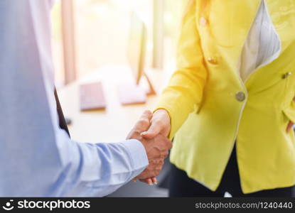 Business people shaking hands standing with colleagues after meeting or negotiation business man and business woman teamwork partnership and handshake success. Man and woman are shaking hand in office