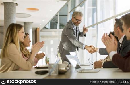 Business people shaking hands while sitting by the desk in the office