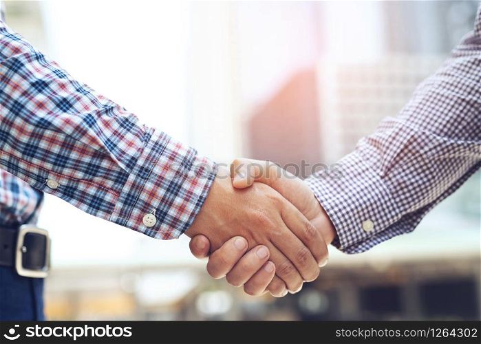 Business people shaking hands while standing with colleagues after meeting
