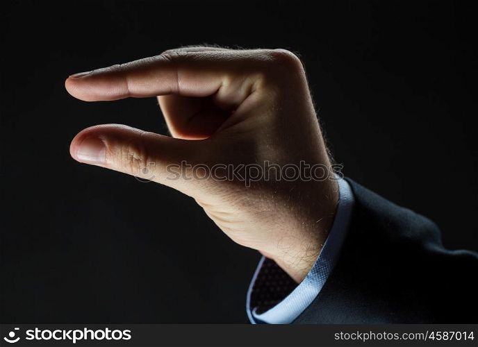 business, people, sign language and gesture concept - close up of businessman hand showing small size over black background