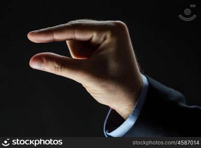 business, people, sign language and gesture concept - close up of businessman hand showing small size over black background