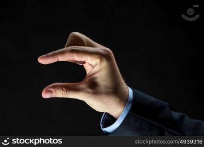 business, people, sign language and gesture concept - close up of businessman hand showing small size over black background. close up of businessman hand showing small size