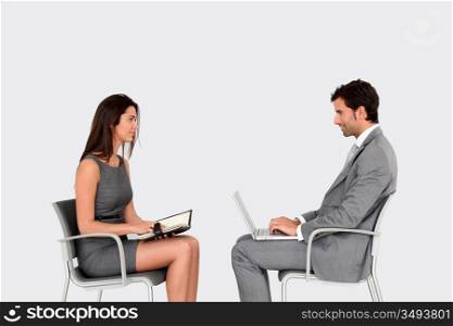Business people sitting face to face on grey background