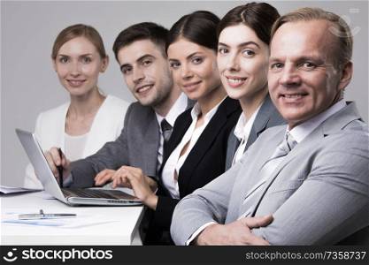 Business people sitting in a row and working together with laptop and documents. Business people sitting in a row