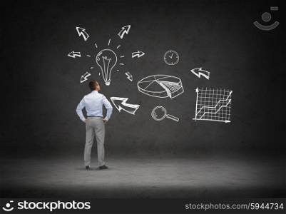 business, people, startup and strategy concept - businessman looking at business idea scheme over concrete room background from back