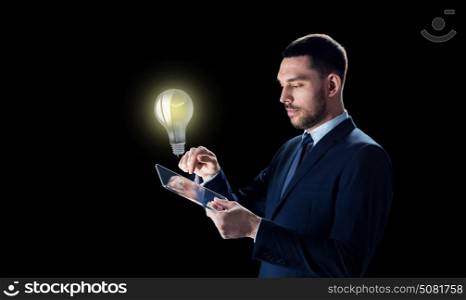 business, people, startup idea, inspiration and modern technology concept - businessman in suit working with transparent tablet pc computer and lightbulb over black background. businessman with tablet pc and lightbulb