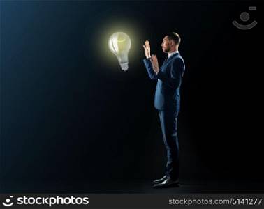 business, people, startup idea, inspiration and office concept - businessman in suit with lightbulb over black background. businessman with lightbulb over black background