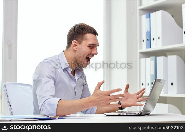 business, people, stress, fail and technology concept - angry businessman with laptop computer and papers shouting in office