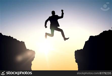business, people, success, achievement and education concept - happy businessman jumping between two rocks