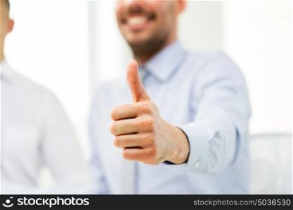 business, people, success and gesture concept - hand of smiling businessman showing thumbs up at office. hand of smiling businessman showing thumbs up