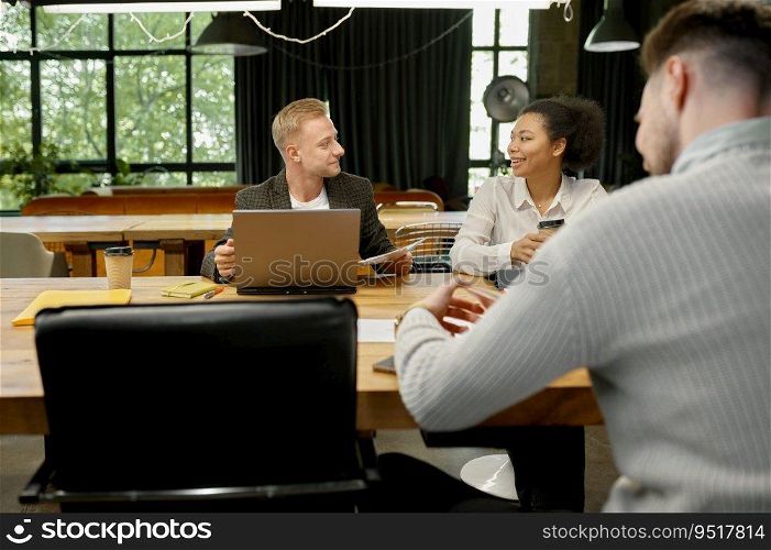 Business people talking and smiling during team meeting in office. Colleagues collaboration concept. Business people using gadgets talking and smiling during meeting in office