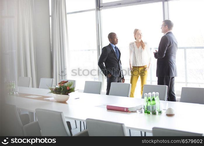 Business people talking while standing by conference table in office