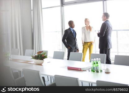 Business people talking while standing by conference table in office