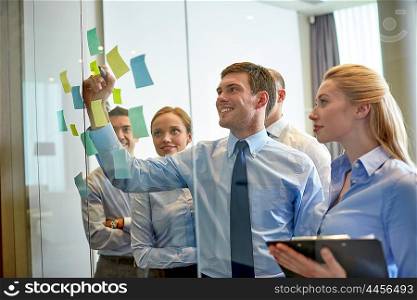 business, people, teamwork and planning concept - smiling business team with marker and stickers working in office