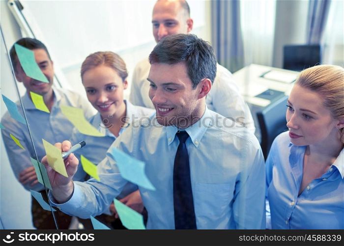 business, people, teamwork and planning concept - smiling business team with marker and stickers working in office