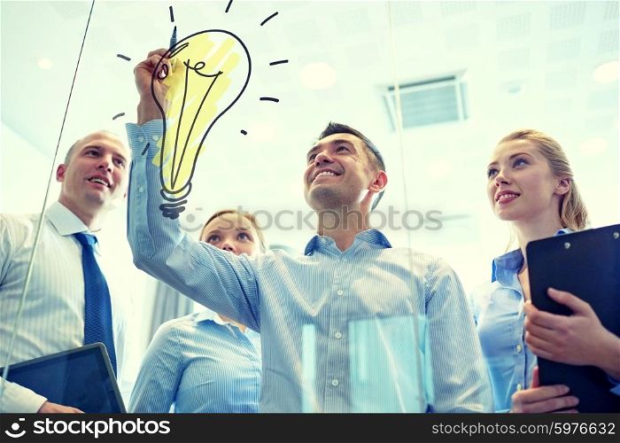 business, people, teamwork and planning concept - smiling business team with marker and light bulb doodle working in office. smiling business people with marker and stickers