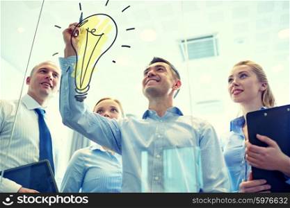business, people, teamwork and planning concept - smiling business team with marker and light bulb doodle working in office. smiling business people with marker and stickers