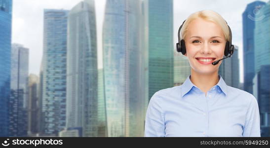 business, people, technology and communication concept - happy female helpline operator in headset over city background