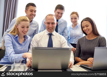 business, people, technology and communication concept - smiling business team with laptop computer making video conference in office