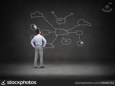 business, people, technology and connectivity concept - businessman looking at cloud computing scheme over concrete room background from back