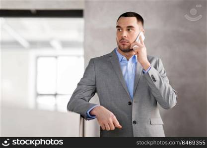 business people, technology and corporate concept - businessman calling on smartphone at office. businessman calling on smartphone at office