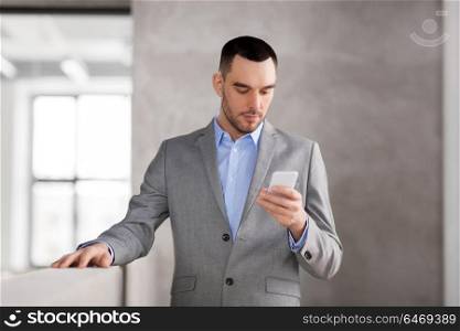 business people, technology and corporate concept - businessman with smarphone at office. businessman with smarphone at office
