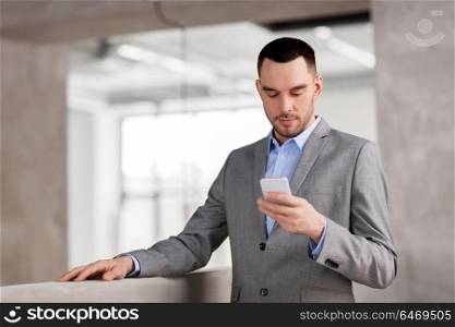 business people, technology and corporate concept - businessman with smarphone at office. businessman with smarphone at office