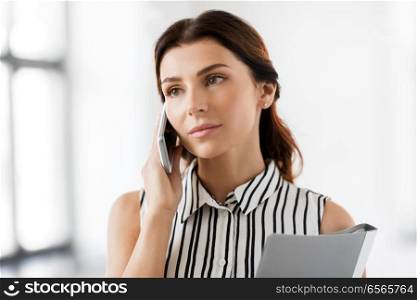 business people, technology and corporate concept - businesswoman or realtor with folder calling on smartphone at office. businesswoman calling on smartphone at office