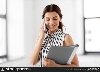 business people, technology and corporate concept - businesswoman or realtor with folder calling on smartphone at office. businesswoman calling on smartphone at office