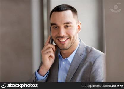 business people, technology and corporate concept - happy smiling businessman calling on smartphone at office. businessman calling on smartphone at office