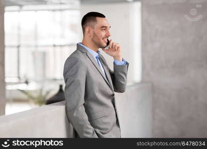 business people, technology and corporate concept - happy smiling businessman calling on smartphone at office. businessman calling on smartphone at office. businessman calling on smartphone at office