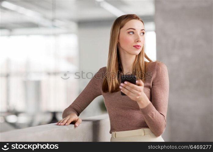 business people, technology and corporate concept - happy smiling businesswoman with smartphone at office. happy businesswoman with smartphone at office