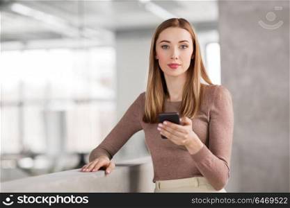 business people, technology and corporate concept - happy smiling businesswoman with smartphone at office. happy businesswoman with smartphone at office