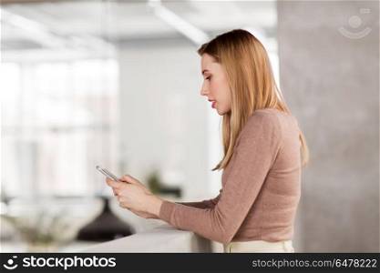 business people, technology and corporate concept - happy smiling businesswoman with smartphone at office. happy businesswoman with smartphone at office. happy businesswoman with smartphone at office