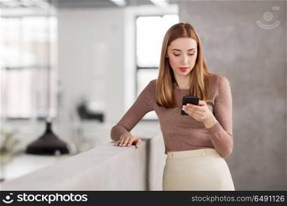 business people, technology and corporate concept - happy smiling businesswoman with smartphone at office. happy businesswoman with smartphone at office. happy businesswoman with smartphone at office