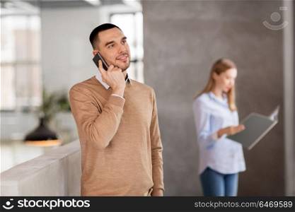 business people, technology and corporate concept - smiling businessman calling on smartphone at office. businessman calling on smartphone at office