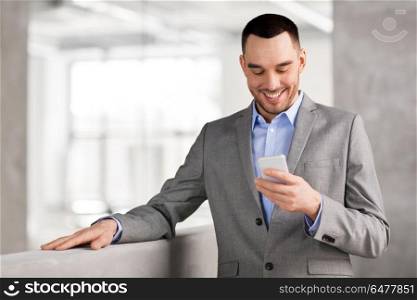 business people, technology and corporate concept - smiling businessman with smarphone at office. smiling businessman with smarphone at office. smiling businessman with smarphone at office
