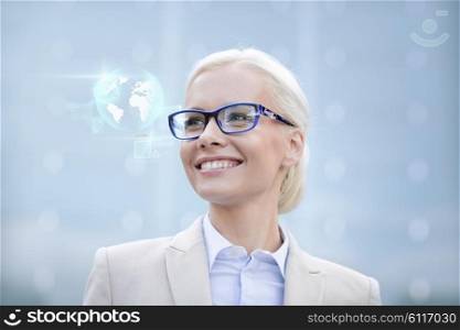 business, people, technology and education concept - young smiling businesswoman in eyeglasses with virtual screens and globe hologram outdoors