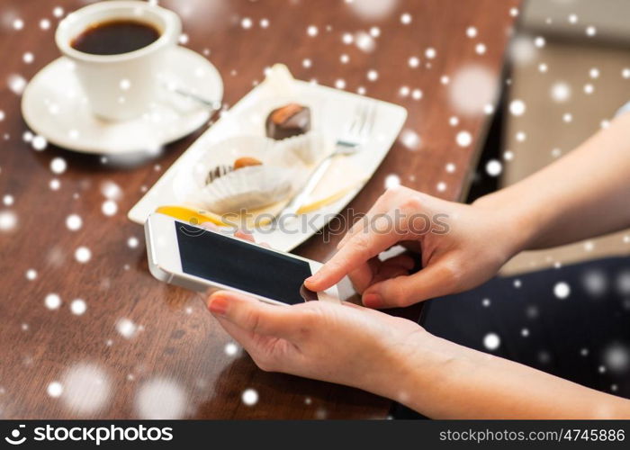 business, people, technology and lifestyle concept - close up of woman with smartphone, coffee and dessert over snow