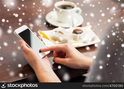 business, people, technology and lifestyle concept - woman with smartphone, coffee and dessert over snow
