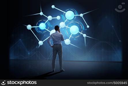 business, people, technology and science concept - businessman looking at virtual molecule projection over dark background from back. businessman looking at virtual molecule projection
