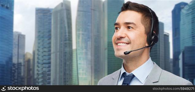 business, people, technology and service concept - smiling businessman in headset over city background