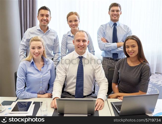 business, people, technology and teamwork concept - smiling business team with laptop computers working in office
