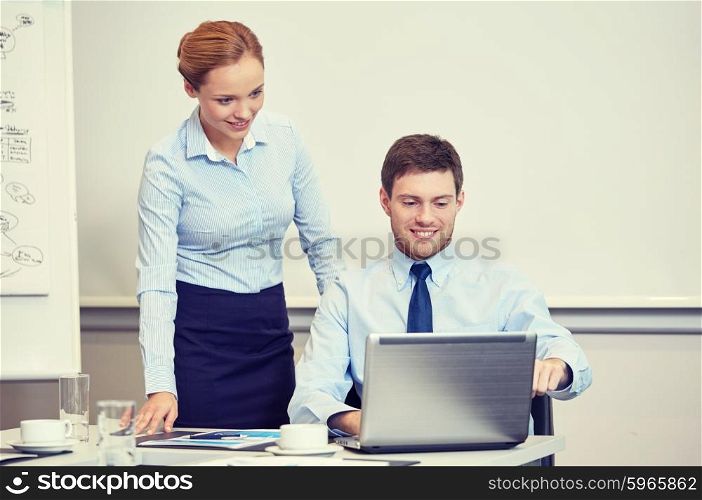 business, people, technology and teamwork concept - smiling businessman and businesswoman with laptop computer meeting and talking in office