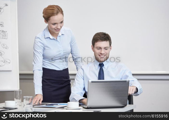 business, people, technology and teamwork concept - smiling businessman and businesswoman with laptop computer meeting and talking in office