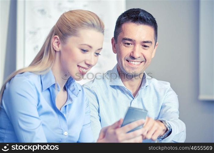 business, people, technology and teamwork concept - smiling businessman and businesswoman with smartphones meeting in office