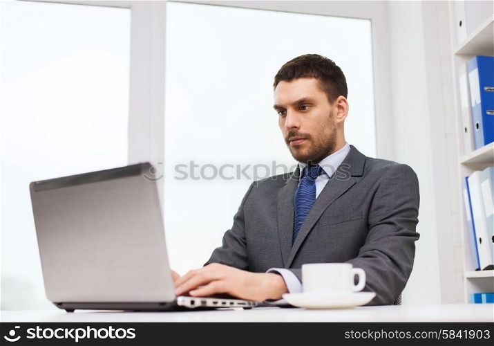 business, people, technology and work concept - businessman sitting in front of laptop and typing in office