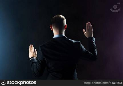 business, people, technology, cyberspace and virtual reality concept - businessman in suit something invisible over dark background. businessman touching something invisible