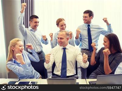 business, people, technology, gesture and teamwork concept - smiling business team raising hands and celebrating victory in office