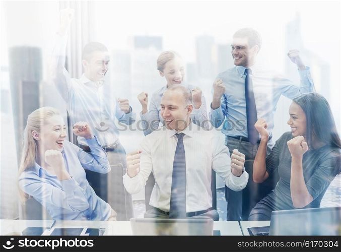 business, people, technology, gesture and teamwork concept - smiling business team raising hands and celebrating victory in office